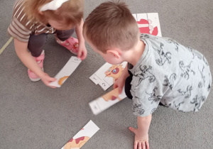 Dziewczynka z chłopcem z grupy Biedronki układa na dywanie puzzle przedstawiające psa.