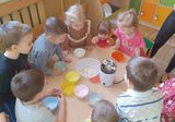Dzieci z grupy Krasnale siedzą przy stoliczku i patrzą jak powstaje popcorn.