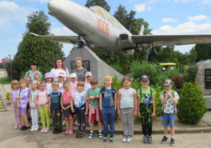 Zdjęcie przedstawia grupę „Smerfy” pozującą przy pomniku ku czci poległych pilotów.