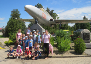 Zdjęcie przedstawia grupę „Tropiciele” pozującą przy pomniku ku czci poległych pilotów.