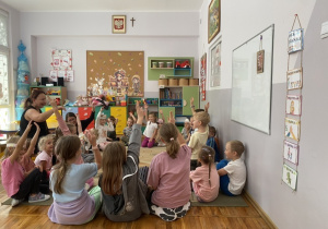 Dzieci siedzą na dywanie i aktywnie odpowiadają na pytania dotyczące czytanego opowiadania.