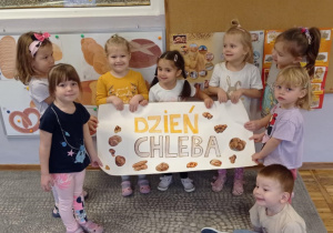 Zdjęcie przedstawia dzieci prezentujące skończony plakat pt.: „Dzień Chleba”.