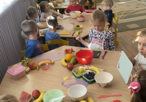 Na zdjęciu widzimy całą grupę przygotowującą się do wykonania sałatki owocowej.