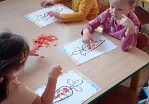 Zdjęcie przedstawia dzieci podczas pracy plastycznej przy stoliku.