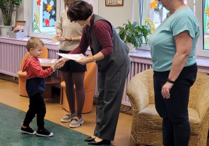 Pani Dyrektor gratuluje i wręcza dyplom chłopcu.