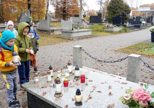 5.Dwóch chłopców trzymających w dłoniach znicze, które postawią na pomniku.