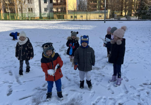 Dzieci lepią śnieżki na boisku szkolnym.