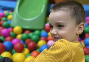 Chłopiec pozuje do zdjęcia w basenie z kulkami