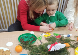 Chłopiec z grupy Słoneczka wraz z mamą wykonują ozdobę świąteczną.