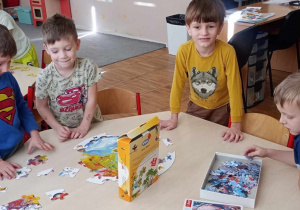 Czterej chłopcy wspólnie układają puzzle.