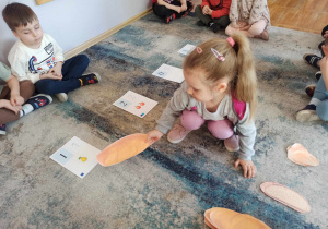 Dziewczynka z grupy „Słoneczka” podczas zabawy w segregowanie pieczywa według wskazanej cyfry.