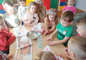 Chłopiec z grupy „Słoneczka” formuje bułeczki z przygotowanego ciasta.
