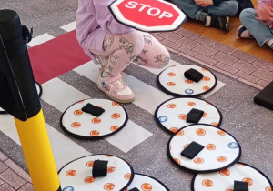 Dziewczynka z grupy Tropiciele spośród znaków wybiera znak stop.