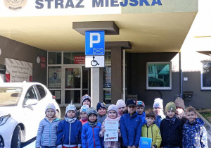 Przedszkolaki z grupy Tropicie pozują do zdjęcia przed budynkiem Straży Miejskiej w Bełchatowie.