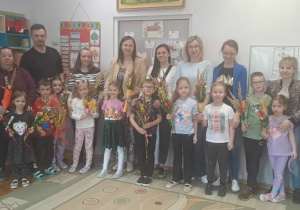 Dzieci z rodzicami pozują do zdjęcia grupowego z wykonanymi palmami Wielkanocnymi.