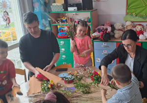 Rodzice z dziećmi wykonują palmę Wielkanocną.