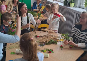 Dzieci z rodzicami wspólnie wykonują palmy Wielkanoce.