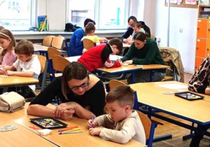 Zdjęcie prezentujące wszystkich zebranych rodziców i dzieci w trakcie ozdabiania drewnianego jajka
