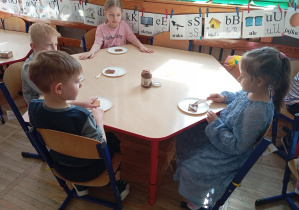 Na zdjęciu dzieci z grupy Odkrywcy smarują ciasteczka czekoladą