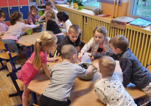 Dzieci wsypują ziemię do doniczek.