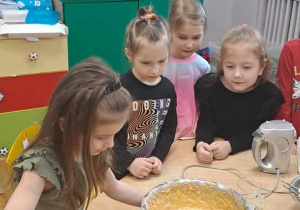 Dziewczynka nakłada ciasto łyżką do blaszki.