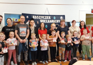 Pszczółki z wykonanymi koszyczkami pozują do zdjęcia wraz z rodzicami.