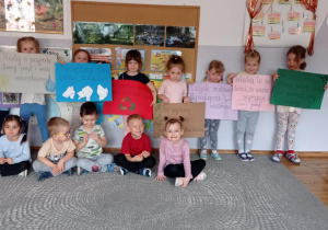 Zdjęcie przedstawia dzieci pozujące do zdjęcia z plakatami zawierającymi ekologiczne hasła.