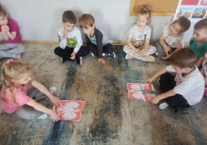 Dzieci z grupy „Słoneczka” układają z puzzli godło narodowe.