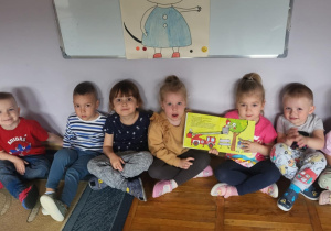 Przedszkolaki pozują do zdjęcia z książeczką o przygodach „Kici Koci”