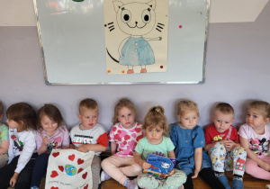 Przedszkolaki pozują do zdjęcia z książeczką o przygodach „Kici Koci” oraz torbą ekologiczną.