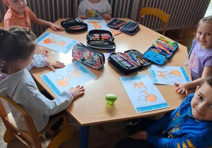 Dzieci siedzą przy stoliku z wykonaną kartą pracy Lisicą Karoliną.