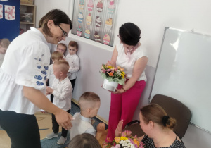 Dzieci wręczają kwiaty, dziękując za pasowanie.
