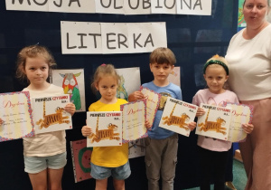 Zadowoleni laureaci konkursu pozują z dyplomami i książkami do pamiątkowego zdjęcia.
