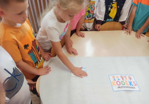 Dziewczynka z grupy „Misie” przykleja obrazek przedstawiający jedną z zasad dobrego zachowania.