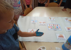 Chłopiec z grupy „Misie” odbija rękę na „Kodeksie Przedszkolaka”.