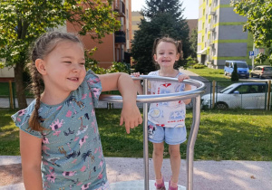 Dwie dziewczynki podczas zabaw na skoczku na placu zabaw.