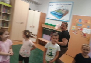 Zdjęcie przedstawia usmiechnięte dzieci i nauczycielkę.