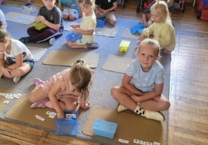 Dzieci siedzą na dywanie, układają imiona z liter.