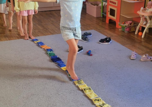 Dziewczynka pokonuje tor przeszkód – chodzi boso po woreczkach.