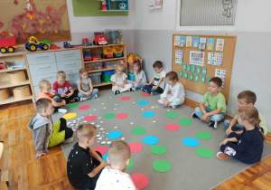 Dzieci z grupy „Misie” siedzą na dywanie pełnym kolorowych kropek