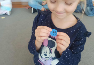 Dziewczynka z grupy „Misie” prezentuje kropkę z uśmiechniętą buzią.