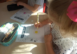 Dziewczynka wykonuje kreatywną pracę plastyczną z wykorzystaniem kropek.