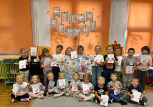 Dzieci z grupy Żabki pozują do zdjęcia z dyplomami, medalami i z plakatem wykonanym z okazji Dnia Kropki.