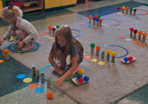 Dziewczynki układają kolorowe piłki według wzoru.