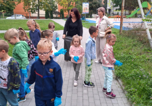 Dzieci z grupy Motylki zbierają śmieci na terenie przedszkola.