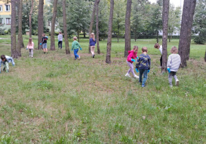 Dzieci w parku zbierają śmieci.