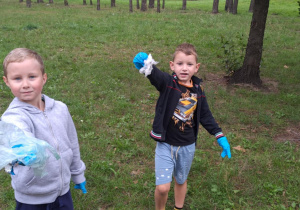 Chłopcy trzymają w rękach znalezione śmieci.