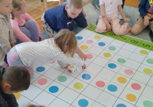 Zdjęcie przedstawia dzieci które pracowały na specjalnej macie edukacyjnej, układając kolorowe kropki według określonych wzorów i koordynatów.