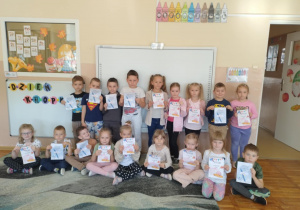 Dzieci z grupy "Smerfy” pozują do grupowego zdjęcia pokazując swoje dyplomy z okazji Dnia Kropki