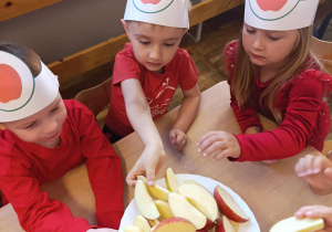 Dzieci częstują się jabłkami.